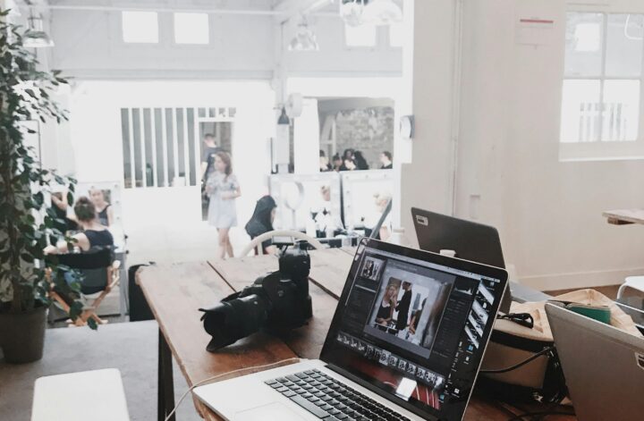 A bright, modern workspace featuring laptops, a camera, and a drawing tablet in an indoor office.
